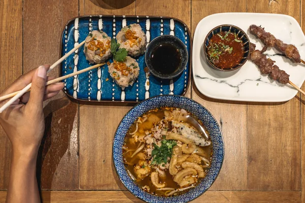 Top view of hand of woman eating asian food with chop sticks. High quality photo