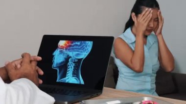 Doctor showing x-ray of pain in the front of the brain on a laptop with woman patient. Migraine Headache illness. High quality 4k footage