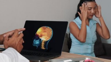 Doctor showing x-ray of pain in the front of the brain on a laptop with woman patient. Migraine Headache illness. High quality 4k footage