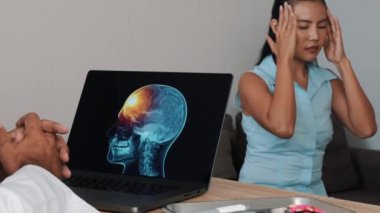 Doctor showing x-ray of pain in the front of the brain on a laptop with woman patient. Migraine Headache illness. High quality 4k footage