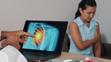 Doctor showing x-ray of pain in the heart on a laptop with woman patient holding her arm. Heart attack symptoms. High quality 4k footage
