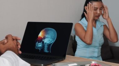 Doctor showing x-ray of pain in the front of the brain on a laptop with woman patient. Migraine Headache illness. High quality 4k footage