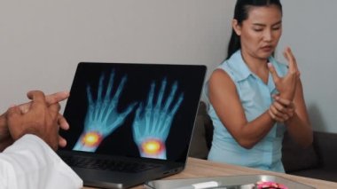 Doctor showing x-ray of pain in the wrists on a laptop with woman patient. High quality 4k footage