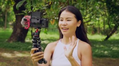 Smiling woman recording video with a camera for vlog and social media. High quality 4k footage