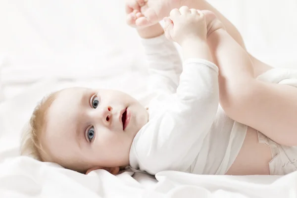 Bebê feliz brincando com seus pés — Fotografia de Stock