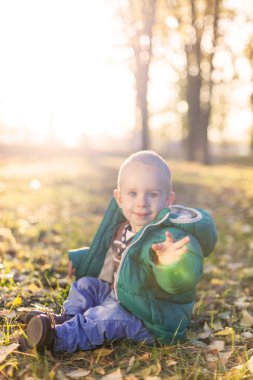 yapraklar sonbaharda oturan mutlu çocuk