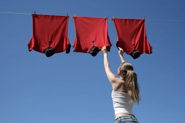 Girl, blue sky and red laundry — Stock Photo, Image