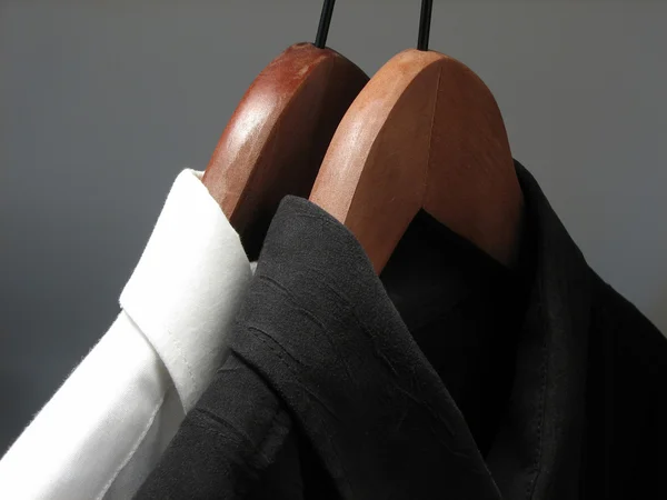 Camisas pretas e brancas em cabides de madeira — Fotografia de Stock