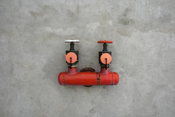 Válvula de ferro vermelha em uma parede de cimento — Fotografia de Stock