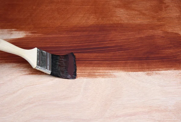 Paint brush painting a wooden surface — Stockfoto