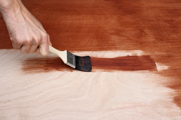 Mão do homem pintando uma superfície de madeira — Fotografia de Stock