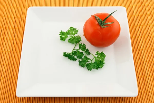 Tomate und Petersilie auf einem quadratischen Teller — Stockfoto