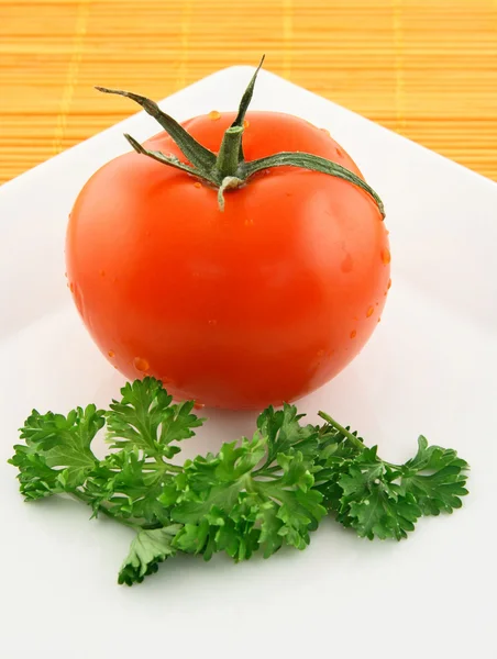 Свежий помидор и петрушка на тарелке — стоковое фото