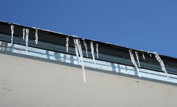 明亮的冬日，在屋顶上的冰柱 — 图库照片