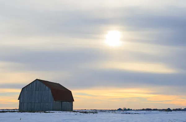 Old wooden barn in a snowy field — Stock Photo, Image
