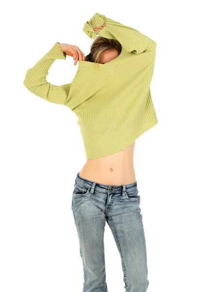Woman in jeans takes off a green sweater — Stock Photo, Image
