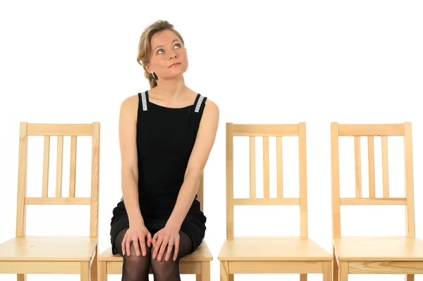 Ung kvinna sitter på en stol och väntar — Stockfoto