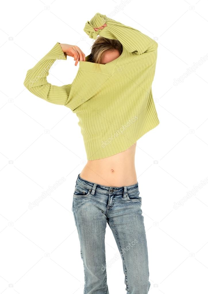 Woman in jeans takes off a green sweater