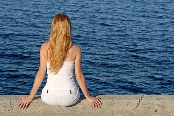 Gadis berambut panjang duduk di tepi laut — Stok Foto