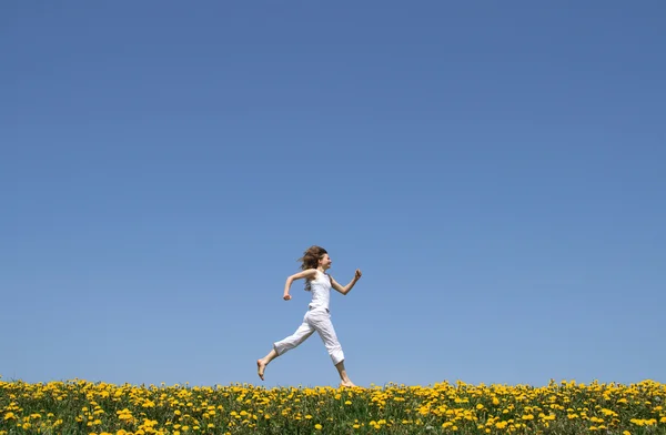 Menina feliz correndo no campo de dente de leão — Fotografia de Stock