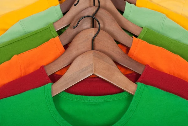Heldere t-shirts op houten hangers — Stockfoto