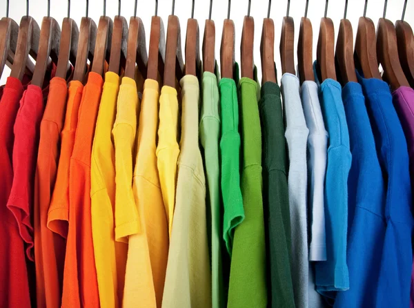 Colors of rainbow, clothes on wooden hangers — Stock Photo, Image