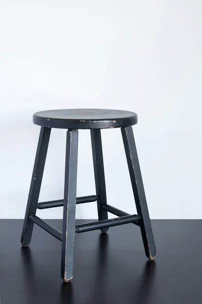 Tabouret noir minable sur surface en bois — Photo