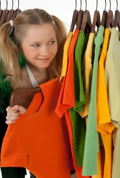 Nieuwsgierig meisje op zoek uit het rek kleding — Stockfoto