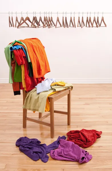 Messy clothes on a chair and empty hangers on the background — Stock Photo, Image