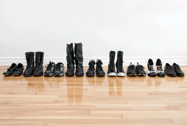 Fila de zapatos y botas en un piso de madera — Foto de Stock