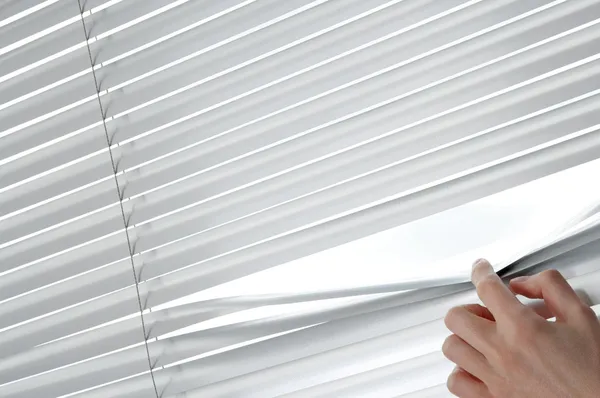 Feminino mão abertura veneziana cortinas com um dedo — Fotografia de Stock