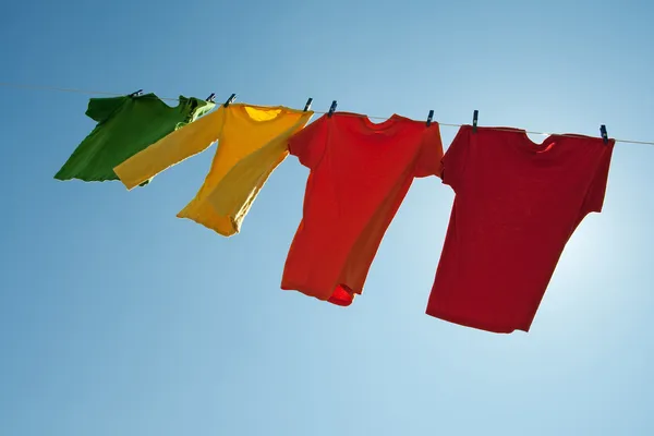 Barevné šaty sušit na modré obloze — Stock fotografie