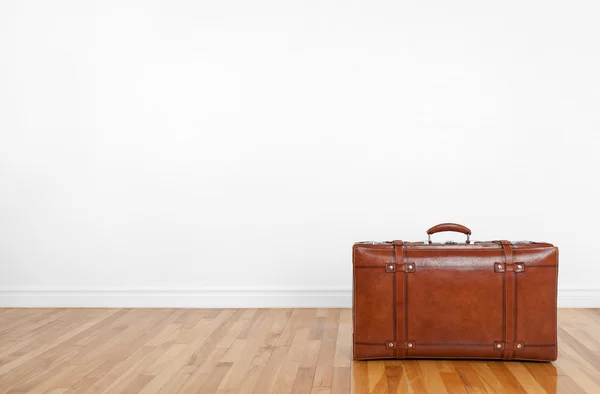 Vintage leather suitcase on a wooden floor — Stock Photo, Image