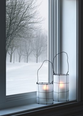 Cozy lanterns and winter landscape seen through the window clipart