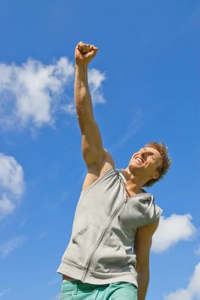 Smiling young man with his arm raised in joy — Stock Photo, Image