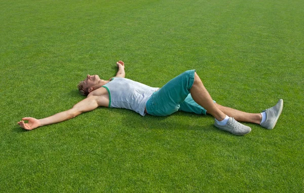 Chico deportivo relajándose en el campo de entrenamiento verde — Foto de Stock