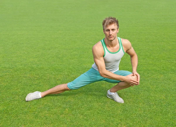 Young man exercising on green field — Stock Photo, Image