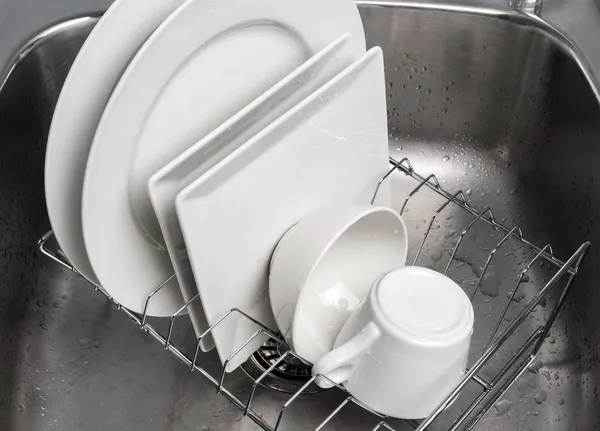 Platos secándose en un estante en el fregadero de la cocina — Foto de Stock