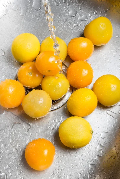 Washing yellow tomatoes and lemons — Stock Photo, Image