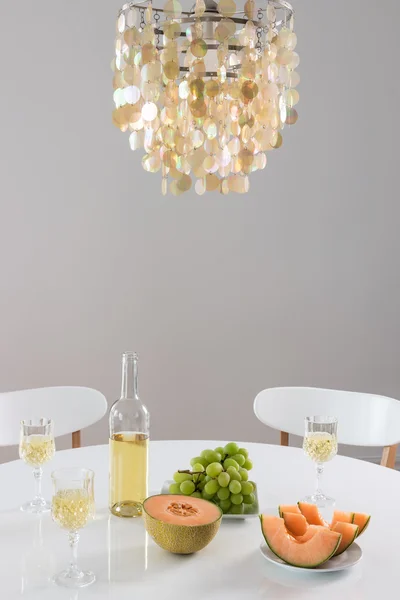 Lustre decorativo e mesa de ajuste com vinho — Fotografia de Stock