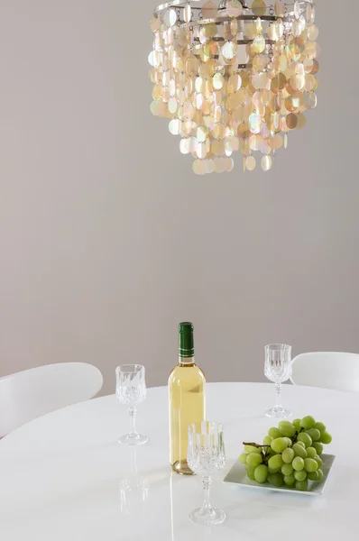 Decorative chandelier and bottle of wine on the table — Stock Photo, Image