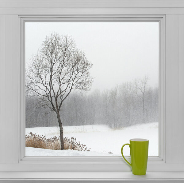Winter landscape seen through the window and green cup