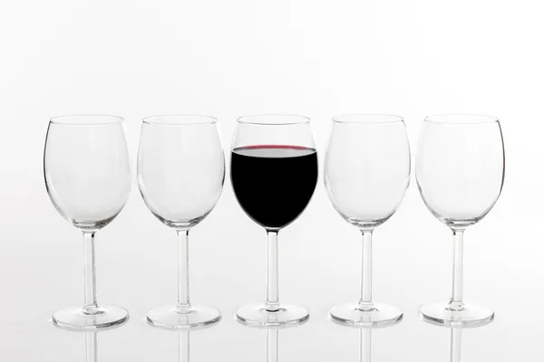 Sklenici červeného vína v řadě prázdných sklenic — Stock fotografie