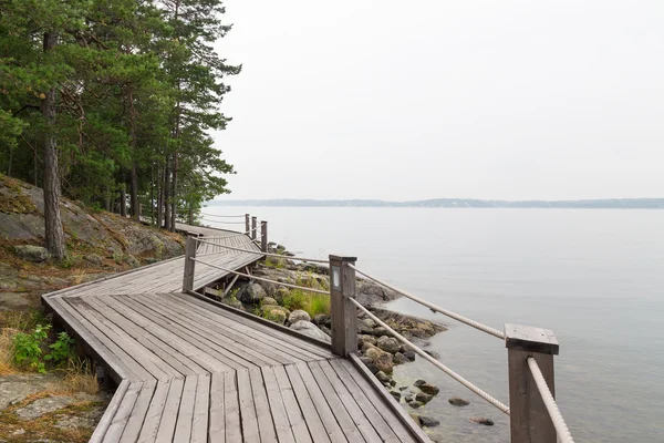 Rocky lakeshore with wooden pathway — Stock Photo, Image