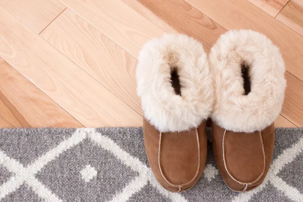 Rug and slippers on wooden floor — Stock Photo, Image