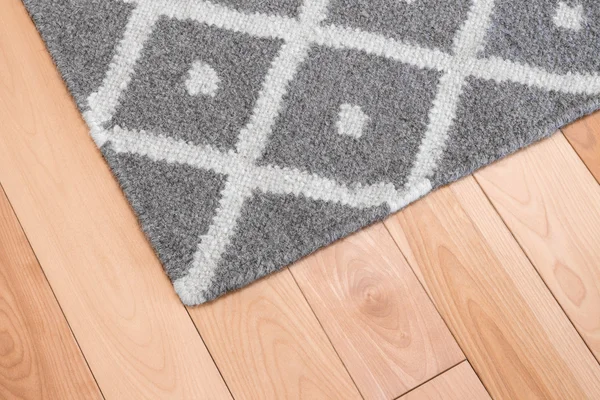 Szary dywan na podłodze drewnianej — Zdjęcie stockowe