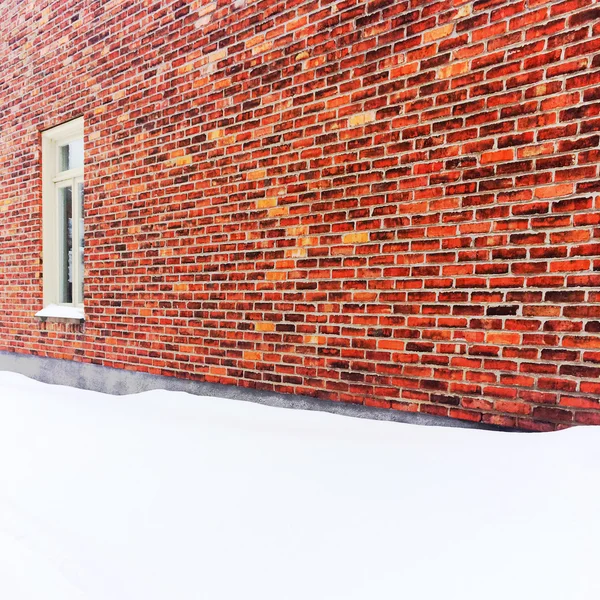 Leere, von Schnee bedeckte Fläche in der Nähe einer Ziegelmauer — Stockfoto
