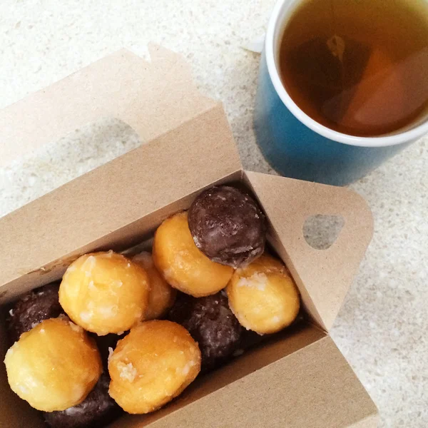 Cup of tea and box of sweet doughnuts — Stock Photo, Image