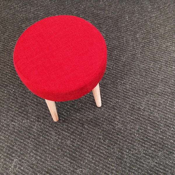 Tabouret rouge sur tapis gris — Photo