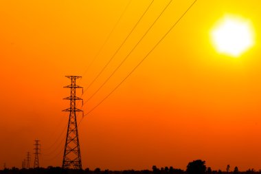 yüksek gerilim güç pole ortasında turuncu gökyüzü ile bir mısır tarlası